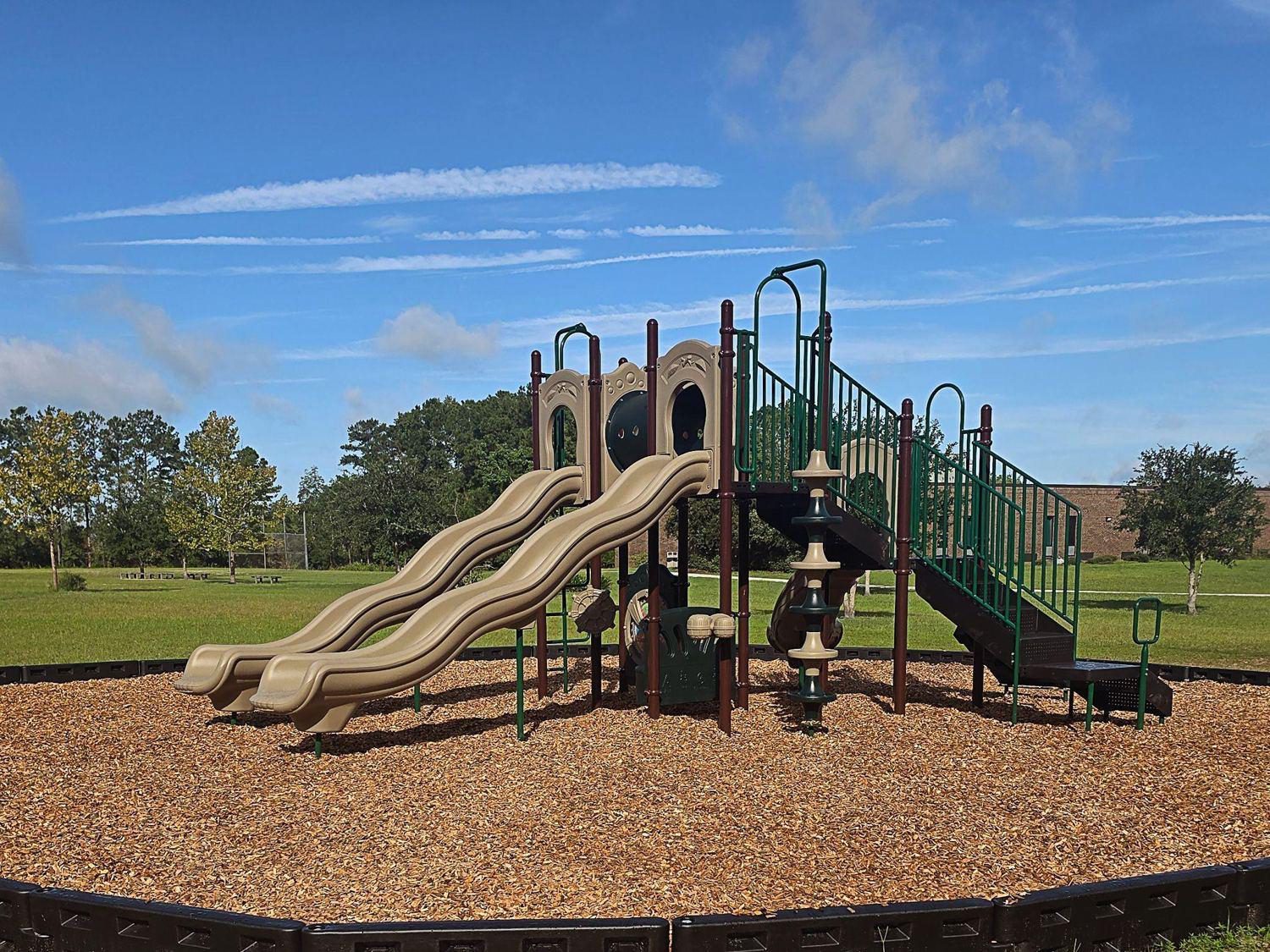 Commercial steel play structure with double wave slides on wood mulch surfacing